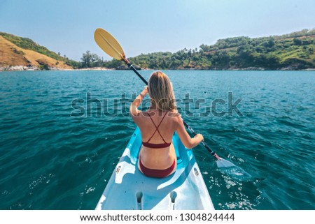 Woman paddling a kayak by the tropical beach. Kayaking tour in Phuket, Thailand