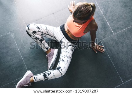 Model wearing fashion sports wear doing exercise at black floor in gym, top view