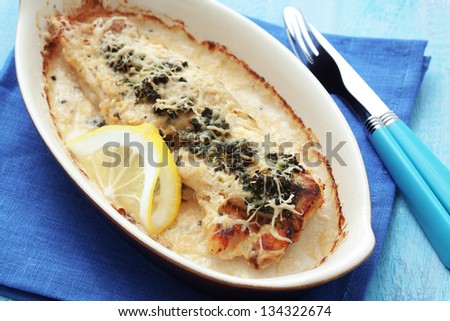Cooked fish with spinach in baking dish on blue wooden table
