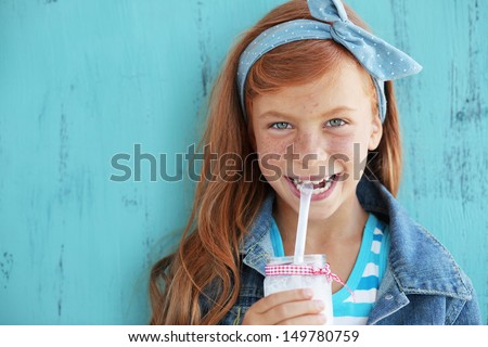 Cute Redheaded Child Drinking Milk On Vintage Blue Background