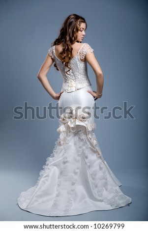 woman with long hair wearing luxurious wedding dress over gray studio