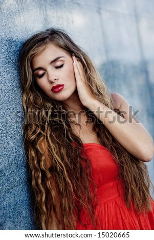 Beautiful model with red sexy lips and long hair staying closing eyes