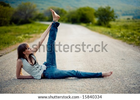 Beautiful teenager girl lying on road holding her leg up