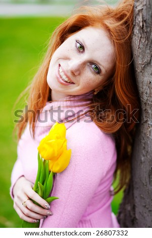 Portrait of beautiful smiling girl with spring flowers posing in park