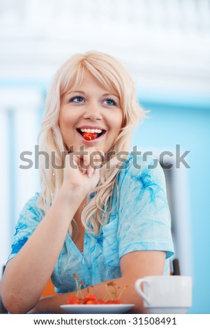 Cheerful attractive girl eating cherry in cafe