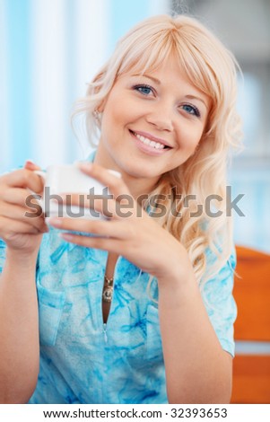 Bright portrait of beautiful smiling girl with cup of tea in cafe