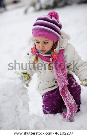 Portrait of cute little child playing with snow outdoors in winter