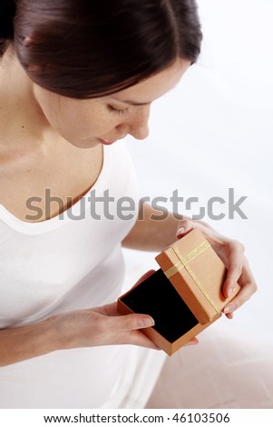 Cute young woman opening gift box close-up