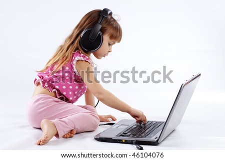 Portrait of funny modern child playing with computer and listening to music in headphones