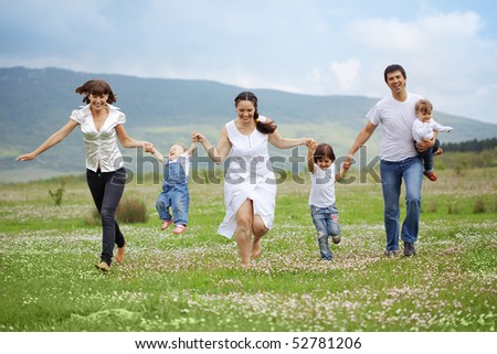 Group of happy parents with children running in field
