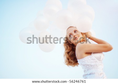 Happy girl with white air balloons in evening sunshine