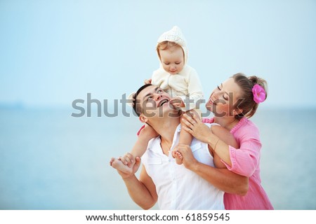 Portrait of young happy parents with child at the beach