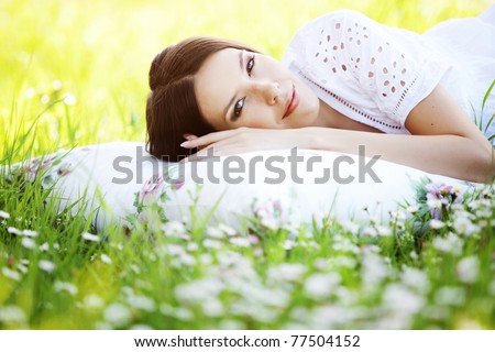 stock photo : Young cute girl resting on soft pillow in fresh spring grass