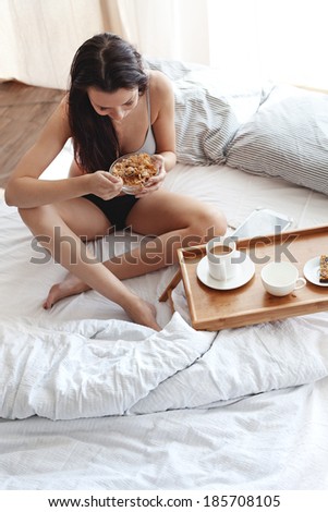 Portrait of 30 years old woman resting in bed with breakfast on a wooden tray at home in morning, still life photo, top view point