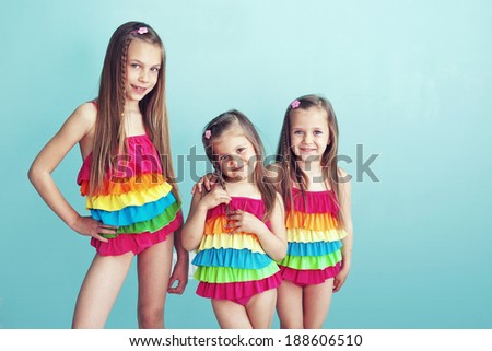 Group of children dressed in same fashion swimsuits posing on aqua blue background