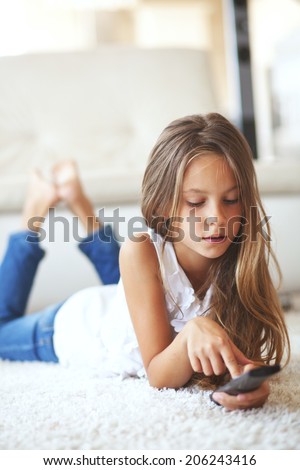8 years old child watching tv laying down on a white carpet at home alone