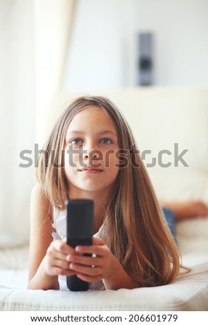 8 years old child watching tv laying down on a sofa at home alone