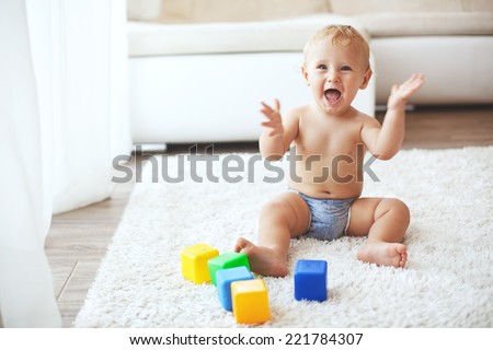 Toddler playing with toys on a white carpet at home