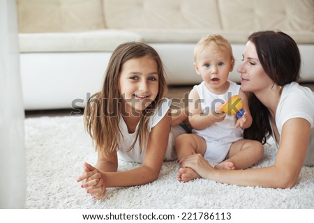 Portrait of a mother with her baby and pre-teen children having fun on white carpet in living room at house