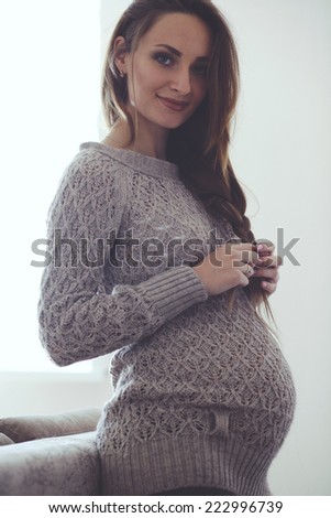 Home cozy portrait of pregnant woman wearing warm cashmere sweater resting at home