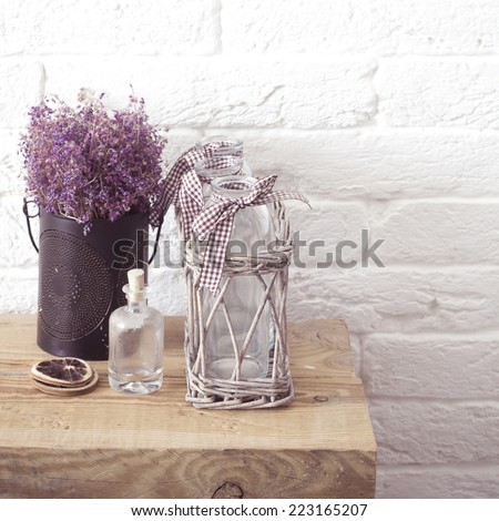 Rustic home decor, provence style. Lavender bouquet of dried field flowers and glass spice jars on wooden bench.
