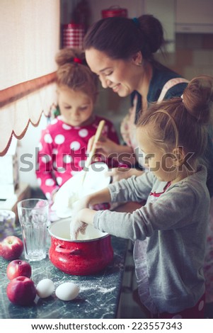 Mother with her 5 years old kids cooking holiday pie in the kitchen to Mothers day, casual lifestyle photo series in real life interior