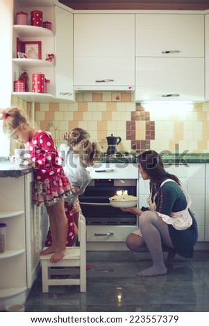 Mother with three kids cooking holiday pie in the kitchen to Mothers day, casual lifestyle photo series in real life interior