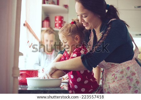 Mother with her 5 years old kids cooking holiday pie in the kitchen to Mothers day, casual lifestyle photo series in real life interior
