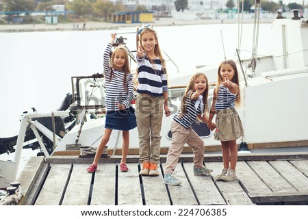 Group of fashion kids sailors wearing navy clothes in marine style enjoying in the sea port