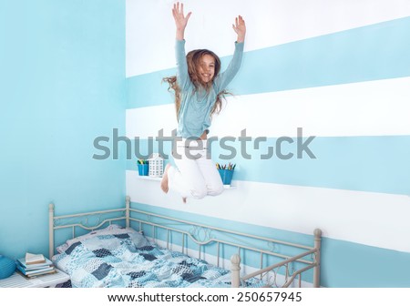 8 years old kid girl jumping on the bed at her room