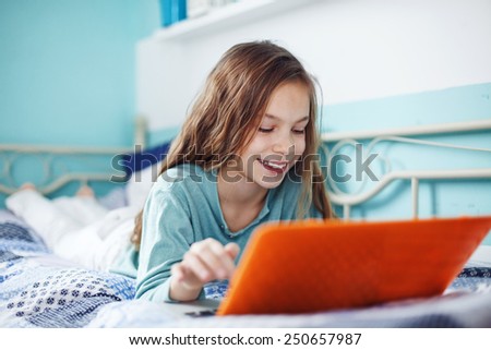 8 years old child having fun using laptop at her bedroom