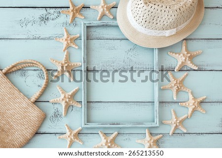 Summer beach decoration: starfishes photo frame with straw hat and handbag on mint wooden background