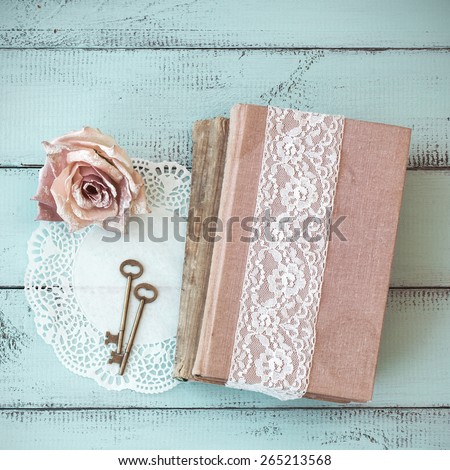 Old books with lace, rose and keys on shabby chic mint background, top view point