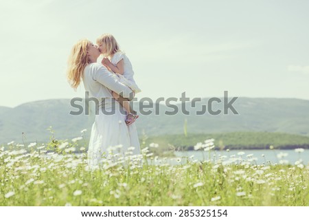 Happy mother playing with her daughter in flower field