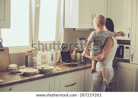 Mom with her 2 years old child cooking holiday pie in the kitchen to Mothers day, casual lifestyle photo series in real life interior