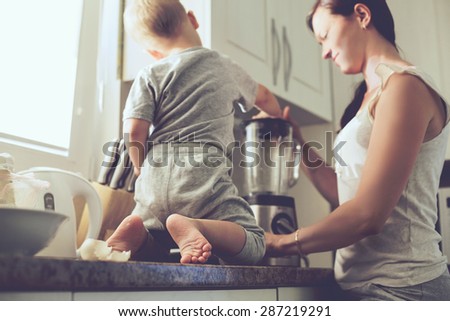 Mom with her 2 years old child cooking holiday pie in the kitchen to Mothers day, casual lifestyle photo series in real life interior. Focus on baby's foots.