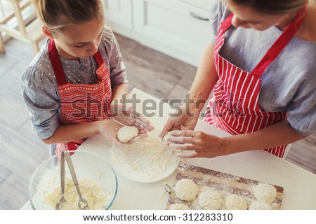 Mom with her 9 years old daughter are cooking in the kitchen to Mothers day, lifestyle photo series in bright home interior