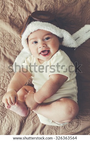 Portrait of a lovable 5 months baby in funny pilot hat, toned image