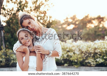 Tween daughter hugging with her mom in summer sunlight
