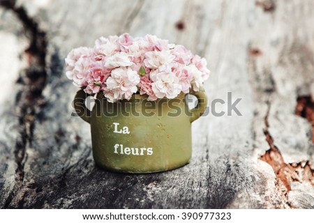 Shabby chic flowers in clay pot on rustic wooden background