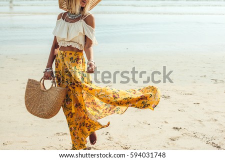 Girl wearing floral maxi skirt walking barefoot on the sea shore, Thailand, Phuket. Bohemian clothing style.