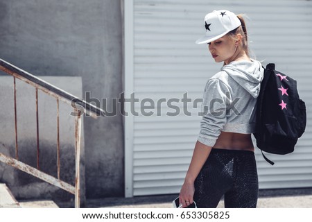 Fitness sporty girl wearing fashion sportswear over street wall, outdoor sports, urban style. Teen model in swag clothes posing outside.