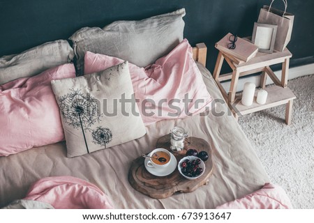 Black loft bedroom and pastel bedding set. Unmade bed with breakfast and reading on tray. Interior decor over blackboard wall. Cozy modern living space.