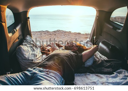 Man relaxing and sleeping inside car trunk. Fall trip in sunset. Freedom travel concept. Autumn weekend.