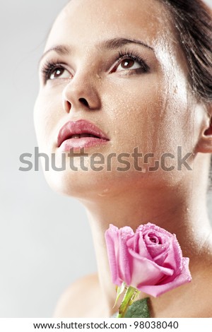 Studio portrait of sensual beautiful woman with rose and water droplets on her face