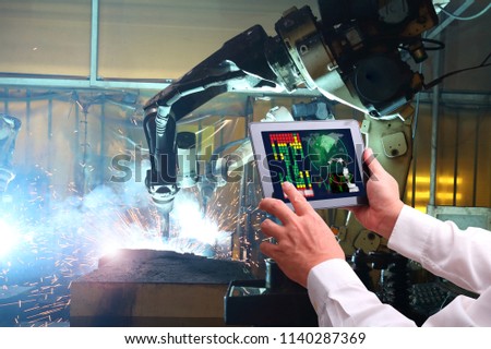 Engineer hand using tablet with machine real time monitoring system software.digital manufacturing operation. Automation robot arm machine in smart factory automotive industrial , Industry 4.0 concept