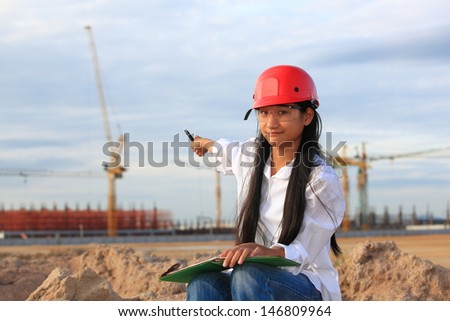 Young Female construction engineer / architect with a workbook at a construction site