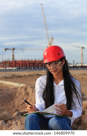 Young Female construction engineer / architect with a workbook at a construction site