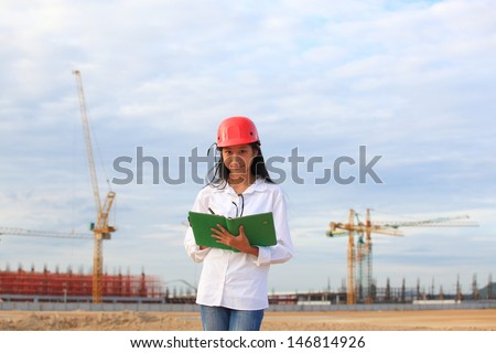 Young Female construction engineer / architect with a workbook and working at a construction site