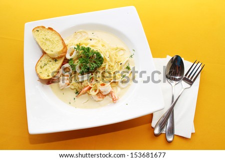 Spaghetti sea food on white plate on yellow table